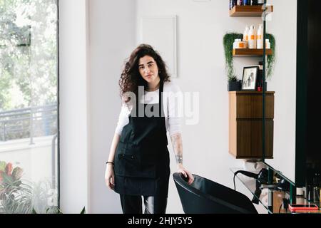 Porträt der weiblichen Besitzerin, die im Friseursalon steht Stockfoto