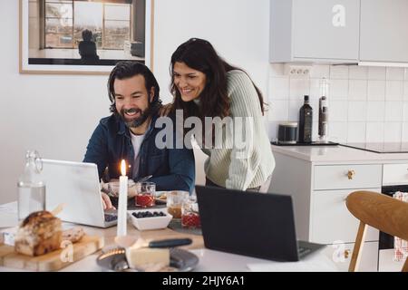 Lächelnde älteres Paar mit Laptop zu Hause Stockfoto