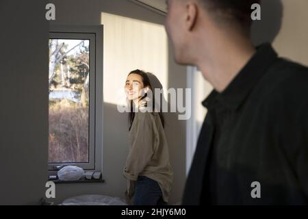 Lächelnde Frau im Gespräch mit Freund zu Hause Stockfoto