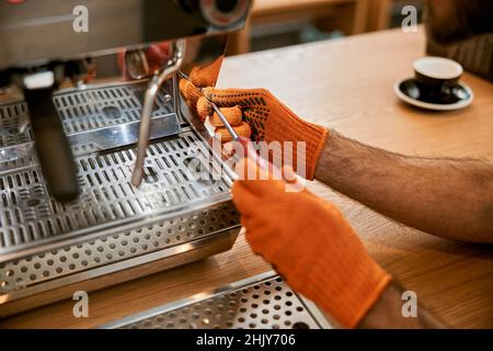 Männliche Hände reparieren Kaffeemaschine mit Schraubendreher Stockfoto