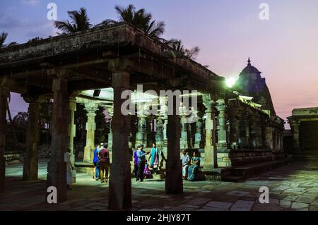 Belur, Karnataka, Indien : Eine Gruppe von Menschen steht in der Dämmerung unter einem der Tempel innerhalb des Channakeshava Temple Complex. Stockfoto