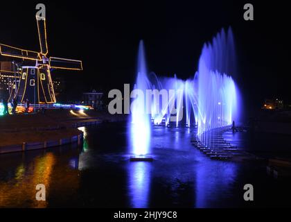 Wasserbrunnen und eine Windmühle in der Nacht Stockfoto