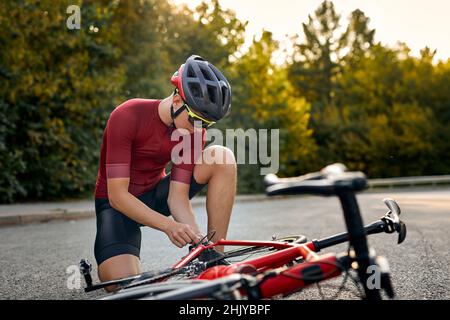 Männlich mit Halt, im Freien, Befestigung Fahrrad durch eigene Kräfte, Änderungen Details, Probleme mit der Bewegung, Sportler kaukasischen Sportler trägt sportliche Stockfoto