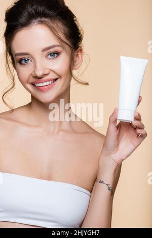 Fröhliches Modell Halteböhrchen mit Lotion isoliert auf beige Stockfoto