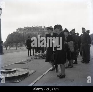 1950s, historisch, Frauen Zivilisten, einige Kriegswitwen, zusammen mit Soldaten, Versammeln Sie sich, um am Grab des unbekannten Soldaten am Fuße des Triumphbogens in Paris, Frankreich, ihre Achtung zu zollen. Die Begräbnisstätte eines gefallenen französischen Soldaten aus dem Jahr WW1 ist ein verängstigte Stätte, eine bleibende Erinnerung an die enormen Opfer des großen Krieges. Stockfoto