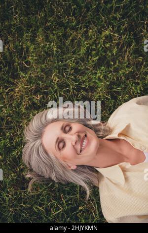 Oben über Hochwinkel-Ansicht Foto von attraktiven reifen Frau genießen liegen grünes Gras Traum Schlaf Erholung im Freien Stockfoto