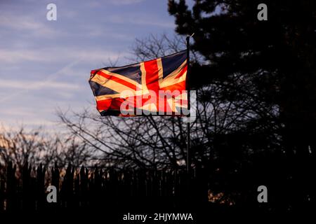 Die Sonne geht über dem Osten von Belfast auf, während die Union Flag im Wind flattert. Stockfoto