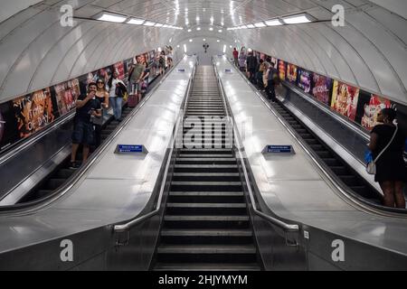 U-Bahn London. Touristen und Reisende auf den Rolltreppen des öffentlichen Nahverkehrssystems der britischen Hauptstadt. Symmetrische Architekturansicht mit niedrigem Winkel. Stockfoto