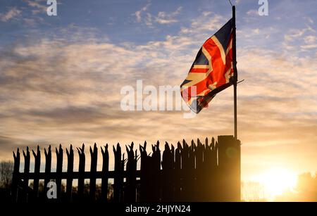 Die Sonne geht über dem Osten von Belfast auf, während die Union Flag im Wind flattert. Stockfoto