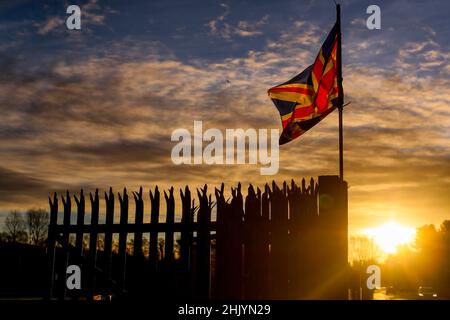 Die Sonne geht über dem Osten von Belfast auf, während die Union Flag im Wind flattert. Stockfoto