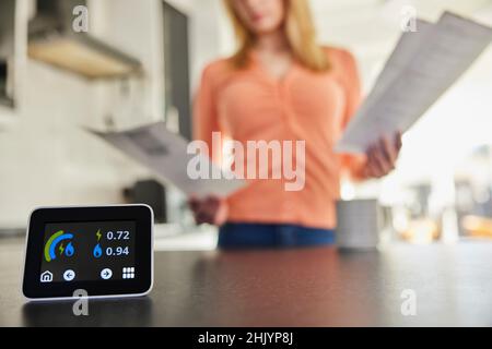 Nahaufnahme Eines Intelligenten Energiezählers In Der Küche, Der Strom- Und Gasnutzung Misst, Während Eine Frau Rechnungen Betrachtet Stockfoto