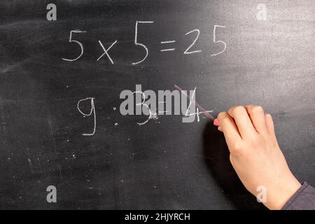 Boy berechnet und schreibt auf einer Tafel Stockfoto