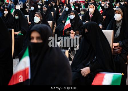 Teheran, Teheran, Iran. 1st. Februar 2022. Eine verschleierte Frau, die eine Schutzmaske trägt, hält eine iranische Flagge, während sie am ersten Tag des Sieges des Jahrestages der Islamischen Revolution auf dem Friedhof Behesht-e Zahra im Süden Teherans vor dem Grab des verstorbenen iranischen Führers Ayatollah Ruhollah Khomeini sitzt (Foto: © Sobhan Farajvan/Pacific Press über ZUMA Press Wire) Stockfoto