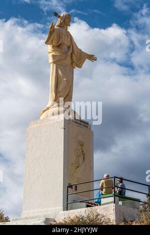 Corazon de Jesus religiöse Statue über Puerto de Mazarron, Murcia, Spanien. Besucher, die nach dem Aufstieg auf den hohen Treppenweg sitzen Stockfoto