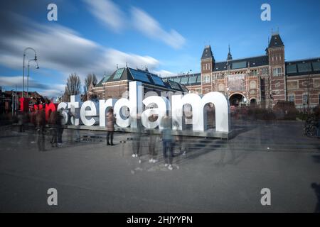 Riesiges Briefschild 'I Amsterdam' vor dem Rijksmuseum. Langzeitbelichtung mit sich bewegenden Wolken, blauem Himmel und verschwommenen Touristen Amsterdam Holland Stockfoto