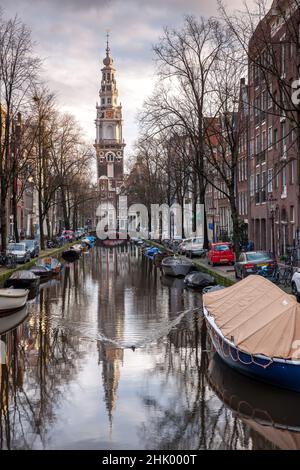 Hillsong Church mit mehreren geparkten Fahrrädern und Booten auf einem Amsterdamer Kanal mit einem Moorhen-Vogel, der im Kanal schwimmt und Wellen im Wat erzeugt Stockfoto