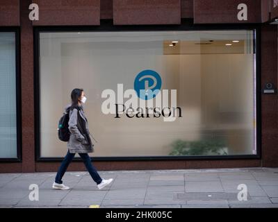 Pendler die Pearson plc, ein britisches Verlags- und Bildungsunternehmen mit Büros in London, kommen mit Covid PPE-Masken an der Zentrale des Pearson Bildungsunternehmens vorbei. Stockfoto