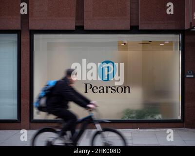Der Mann fährt mit dem Fahrrad am Hauptsitz des Pearson Education Company im Zentrum von London vorbei. Pearson plc ist ein britisches Verlags- und Bildungsunternehmen mit Niederlassungen in London. Stockfoto