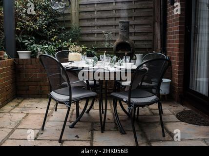 Geburtstagskuchen auf einem dekorierten Esstisch im Garten mit Kerzen Stockfoto