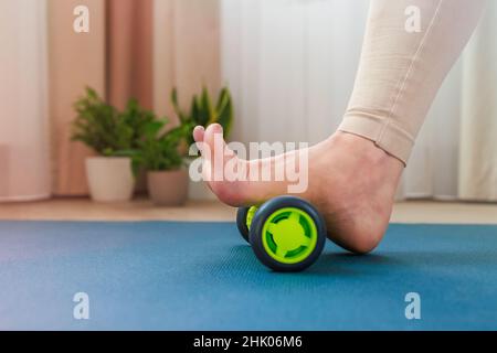 Rollen des oberen Fußbogens mit einer Massagerolle Stockfoto