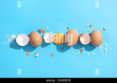 Eier, Eierschale und Eigelb auf blauem Hintergrund braun anbraten. Flache Lay-Komposition. Stockfoto