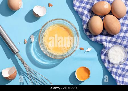Geschlagene Eier auf blauem Hintergrund. Flach liegend. Stockfoto