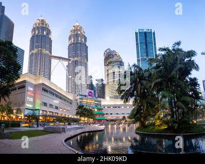 Kuala Lumpur, Malaysia - Januar 2022: Die Petronas Towers und das Suria Einkaufszentrum vom KLCC Park - weltberühmte Wolkenkratzer in Kuala Lumpur City Cen Stockfoto