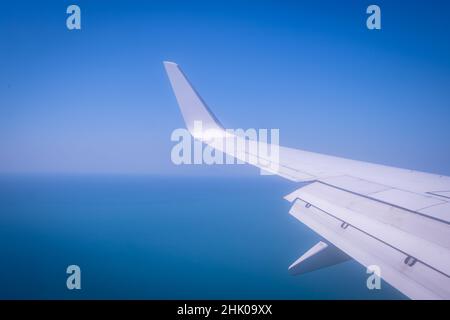 Flugzeug-Flügel gegen blaues Meer und Himmel aus großer Höhe Stockfoto