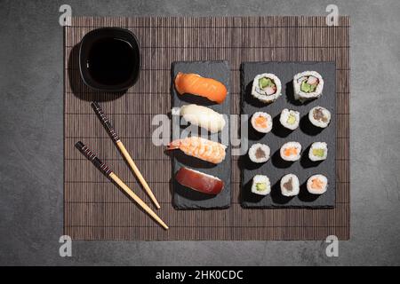 Verschiedene Sushi auf dunklem Hintergrund. Draufsicht. Typisch japanisches Essen. Stockfoto