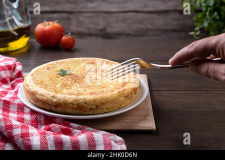 Spanisches Omelett mit Gabel auf rustikalem Hintergrund von Hand abholen. Traditionelle spanische Küche. Stockfoto