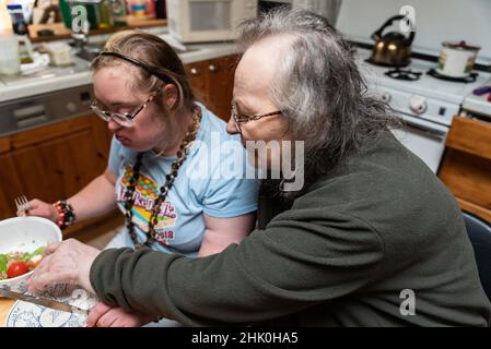 Hachendover, Flämisch-Brabant, Belgien - 09 20 2021: Behinderte 39-jährige Frau und ihre 83-jährige Mutter, die sich zu Hause in der Küche amüsieren.