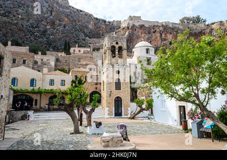 Hauptplatz der Stadt Monemvasia mit Glockenturm und Kirche in Griechenland. Schöner Blick auf den Glockenturm, traditionelle Häuser und mittelalterliche Burgmauern. Stockfoto