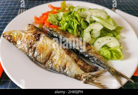 Blick auf plattierte Speisen, gesundes Fischgericht, typisches Gericht der portugiesischen regionalen Küche mit gegrillten Sardinen mit Salat: Rote Paprika, grüne Paprika, sesa Stockfoto