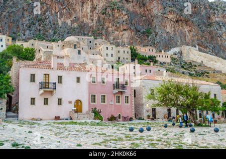 Mittelalterliche Stadt der Insel Monemvasia mit amphitheatralischer Architektur in Griechenland. Alte Burgstadt mit mehrfarbigen Häusern auf einem riesigen Felsen gebaut. Stockfoto