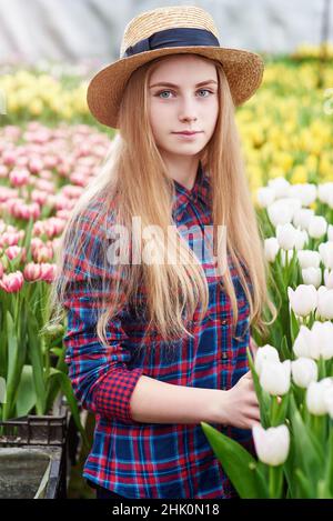 Glücklich lächelnd Teenager Mädchen im Hut mit Gießkanne in Blühender Tulpengarten Stockfoto