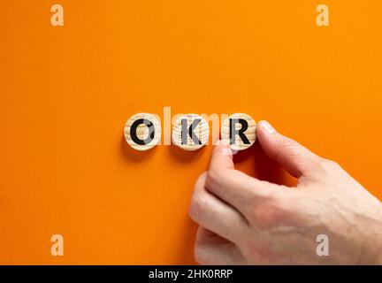 Symbol für OKR, Ziele und Schlüsselergebnisse. Konzeptworte OKR-Ziele und Schlüsselergebnisse auf Holzkreisen auf einem schönen orangefarbenen Hintergrund. Business OKR Stockfoto