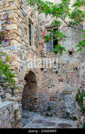 Byzantinische Straße mit traditioneller Allee mit Bogen auf der Insel Monemvasia, Peloponnes, Griechenland. Mittelalterliches Steinhaus mit großen Fenstern Stockfoto