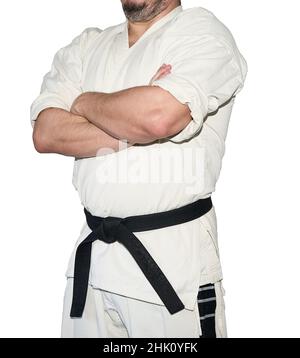 Mann in Karate-Kampfkunstuniform faltet seine Arme isoliert auf dem weißen Hintergrund. Schwarzer Gürtel Stockfoto