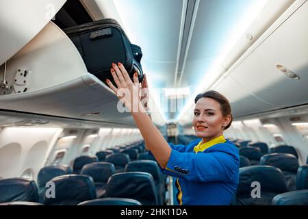 Stewardess: Reisetasche im Gepäckfach über dem Kopf im Flugzeug Stockfoto