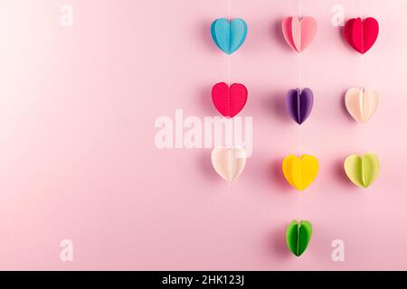 Verschiedene Farben Papier Herzen auf rosa Hintergrund mit Kopierraum. Valentinstag, Muttertag und Feiertag Grußkarte. Mock up. Stockfoto