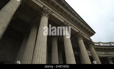 Untere Ansicht der antiken Säulen mit korinthischen Orden. Aktion. Starke Säulen auf dem Hintergrund des bewölkten Himmels. Altes Gebäude mit Portikus. Stockfoto