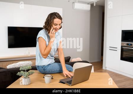 Eine vielbeschäftigte Frau, die mit einem Kunden telefoniert und auf der Tastatur timt, während sie am Schreibtisch sitzt. Multitasking weibliche Büroangestellte Konzept Stockfoto