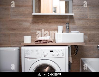 Innenausstattung des Badezimmers. Kompakte Platzierung von Waschbecken, Regal, Waschmaschine und Toilettenschüssel. Stockfoto