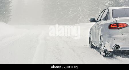 Silbernes Auto bedeckt mit Eis geparkt auf schneebedeckter Straße, Detailansicht von hinten, Hintergrund leerer Platz für Text links Stockfoto