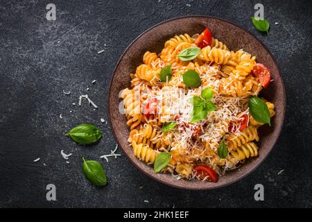 Italienische Pasta alla arrabiata mit Basilikum und Parmesan auf dunklem Tisch. Stockfoto