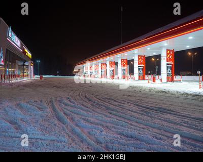 Region Moskau. Russland. 29. Januar 2022. Schneebedeckte Tankstelle Neftmagistral in einer Winternacht. Eine hell erleuchtete Tankstelle in einer Winternacht. Stockfoto