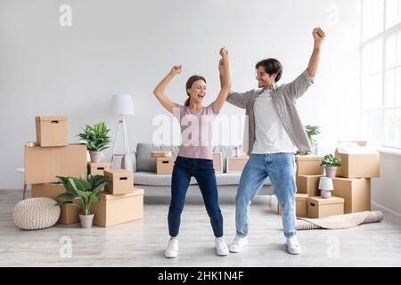 Glücklicher europäischer Tausendjähriger Mann und Dame, die im Wohnzimmer mit Pappkartons tanzen Stockfoto