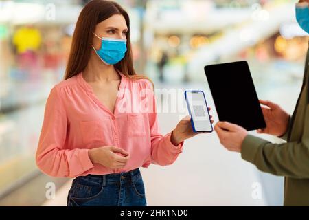 Frau zeigt Smartphone mit QR-Code zu Männlich in Mall Stockfoto
