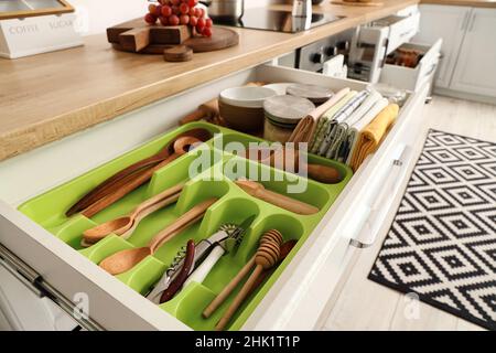 Set mit verschiedenen Küchenutensilien in geöffneten Schubladen Stockfoto