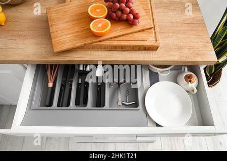 Offene Schublade mit Besteck und frischem Obst auf der Theke in der Küche Stockfoto